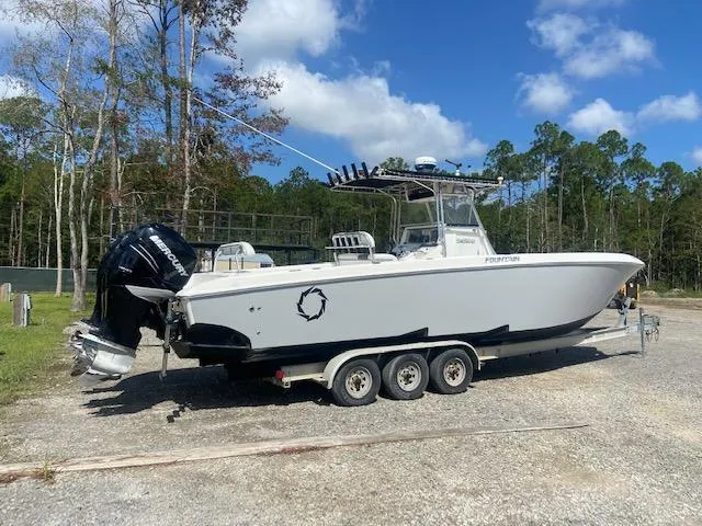 Slide: The Image of 2004 Fountain 34 CC boat on a triple-axle trailer in a wooded area. - 5