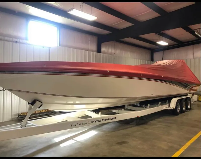 Slide: The Image of 1992 Fountain 42 Lightning boat with red cover on trailer in warehouse. - 2