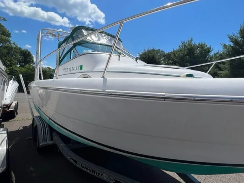 Slide: The Image of 2001 Pro-Line 25 Walkaround boat on trailer under a blue sky. - 6