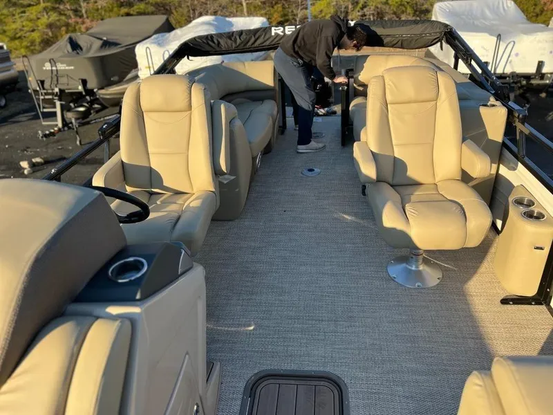 Slide: The Image of 2023 Regency 230 DL3 pontoon boat interior with beige seating and carpet. - 6