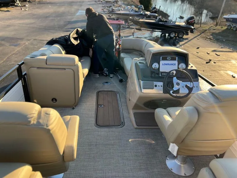 Slide: The Image of 2023 Regency 230 DL3 pontoon boat interior with beige seating and modern dashboard. - 8