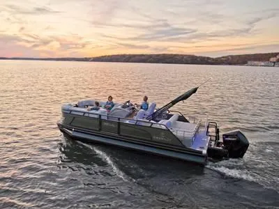 The Image of 2023 Regency 230 LE3 Sport pontoon boat cruising on a lake at sunset. - 1