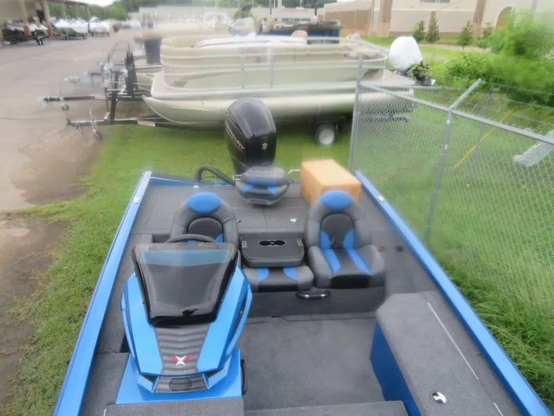 Slide: The Image of 2023 Vexus AVX 181 boat with blue and black interior, parked near other boats. - 17