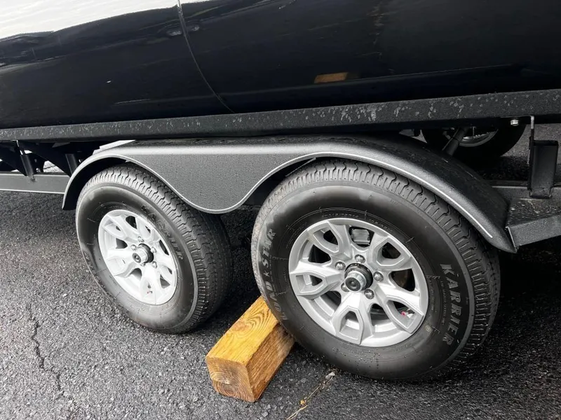 Slide: The Image of 2023 Regency 250 LE3 trailer wheels on asphalt, secured with a wooden block. - 14