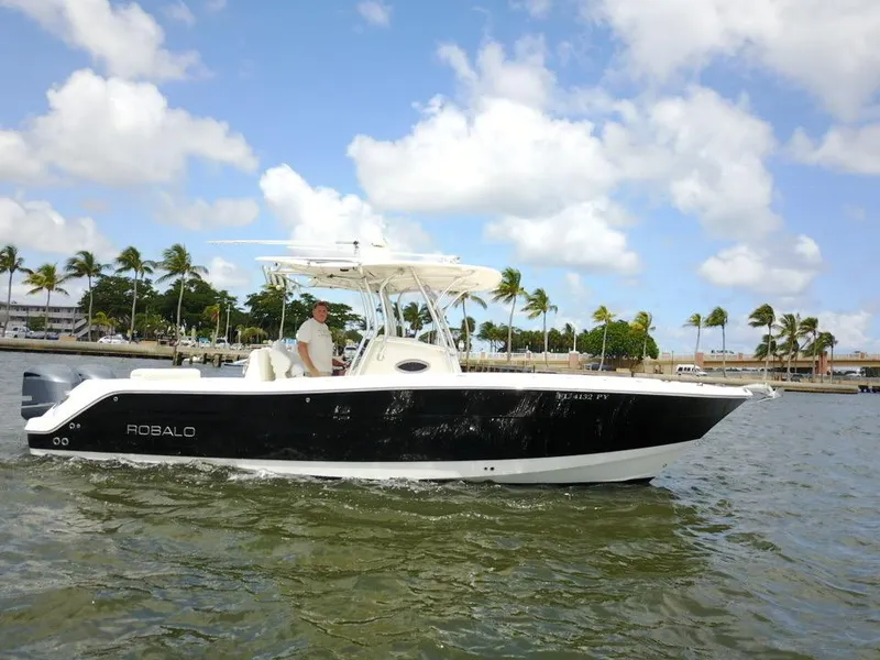 The Image of 2015 Robalo R300 Center Console boat cruising on water with palm trees in the background. - 0