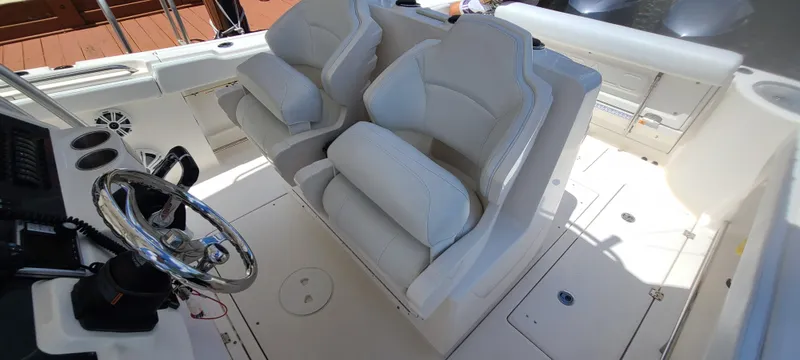 Slide: The Image of 2015 Robalo R300 Center Console boat interior with dual white captain's chairs and steering wheel. - 27