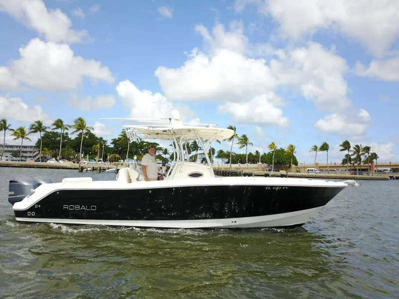 Slide: The Image of 2015 Robalo R300 Center Console boat cruising on a sunny day with palm trees in the background. - 45