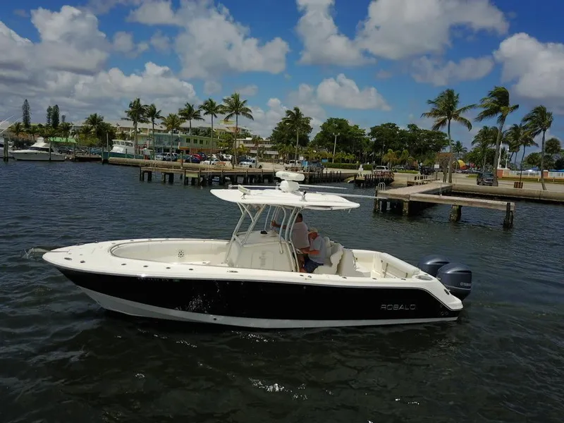 Slide: The Image of 2015 Robalo R300 Center Console boat on water near a dock with palm trees. - 47