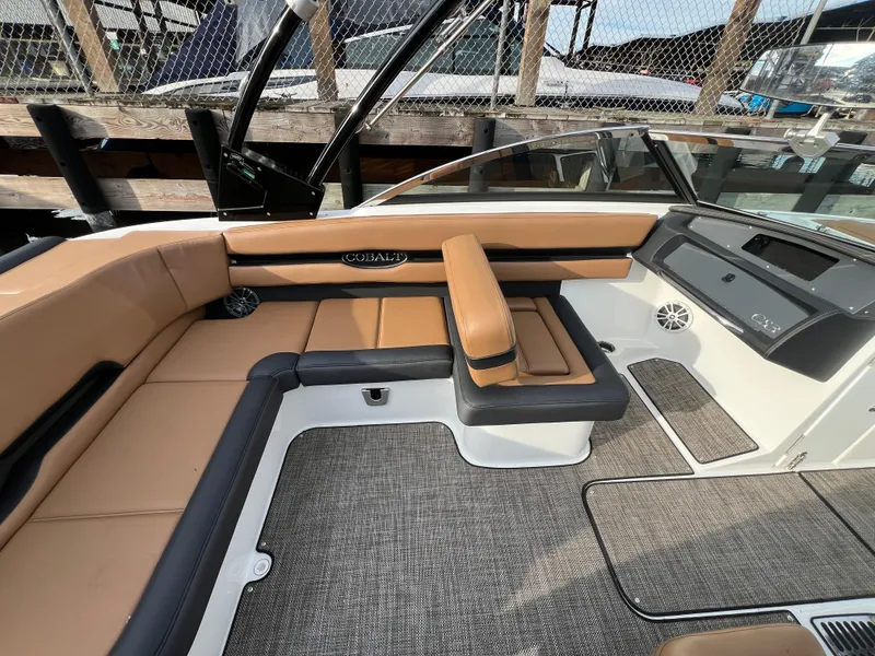 Slide: The Image of 2023 Cobalt CS23 Surf boat interior with tan and black seating, modern dashboard, and carpeted flooring. - 11