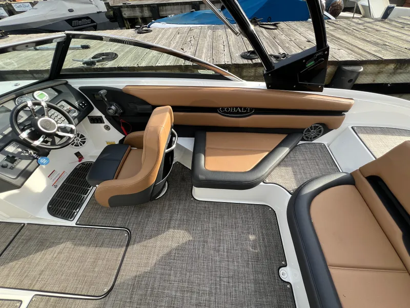 Slide: The Image of 2023 Cobalt CS23 Surf boat interior with tan and black seating, modern dashboard, and steering wheel. - 13