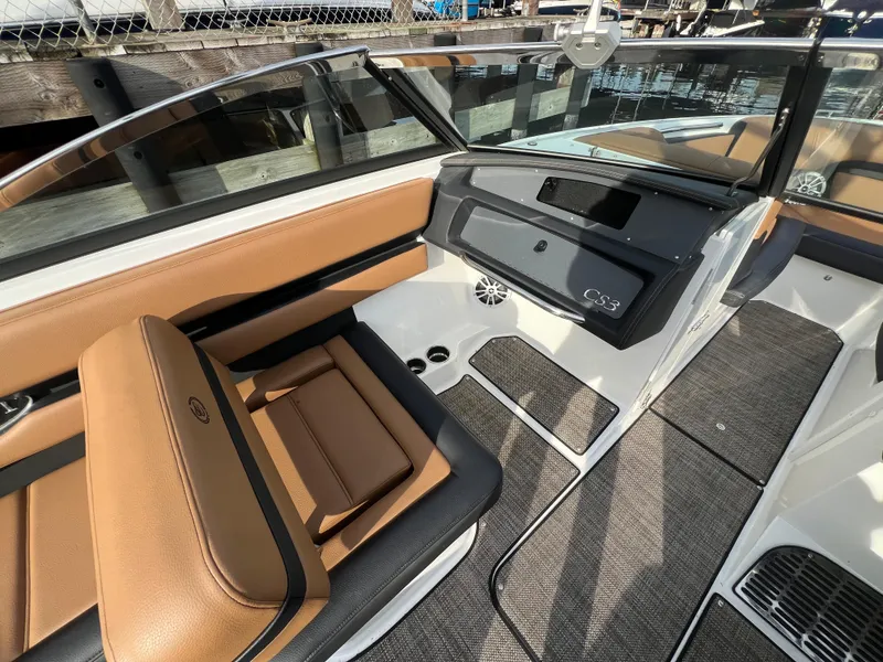 Slide: The Image of 2023 Cobalt CS23 Surf boat interior with tan and black seating, docked by water. - 15