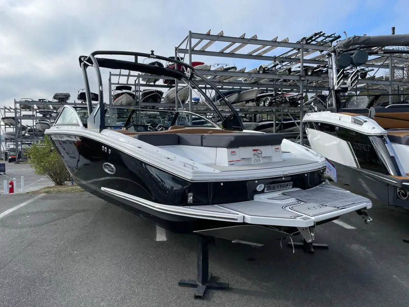Slide: The Image of 2023 Cobalt CS23 Surf boat displayed in a marina with other boats. - 23