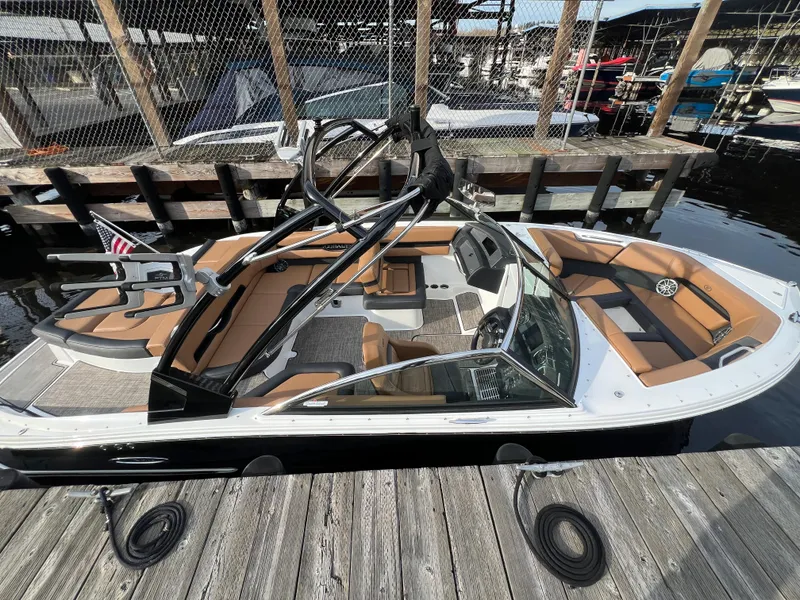 Slide: The Image of 2023 Cobalt CS23 Surf boat docked, featuring sleek design and spacious interior seating. - 3