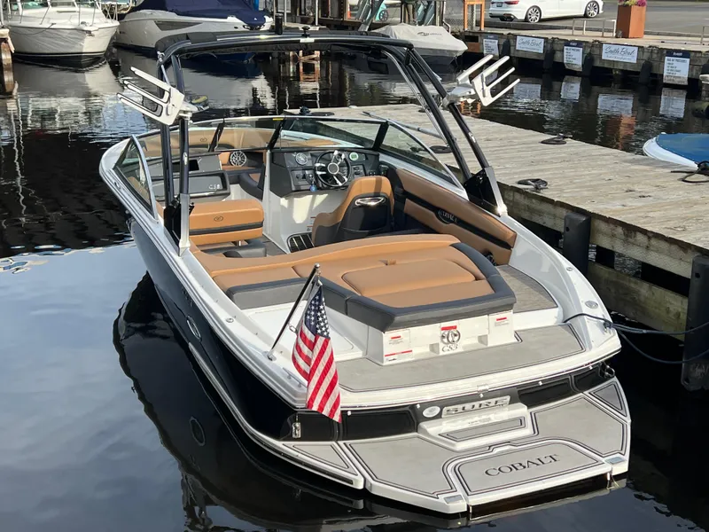 Slide: The Image of 2023 Cobalt CS23 Surf boat docked, featuring sleek design and American flag. - 6