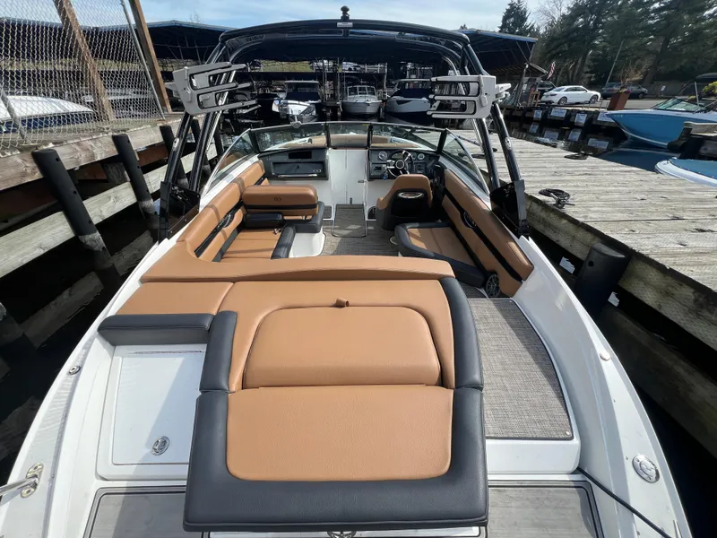 Slide: The Image of 2023 Cobalt CS23 Surf boat with tan and black seating, docked at a marina. - 9