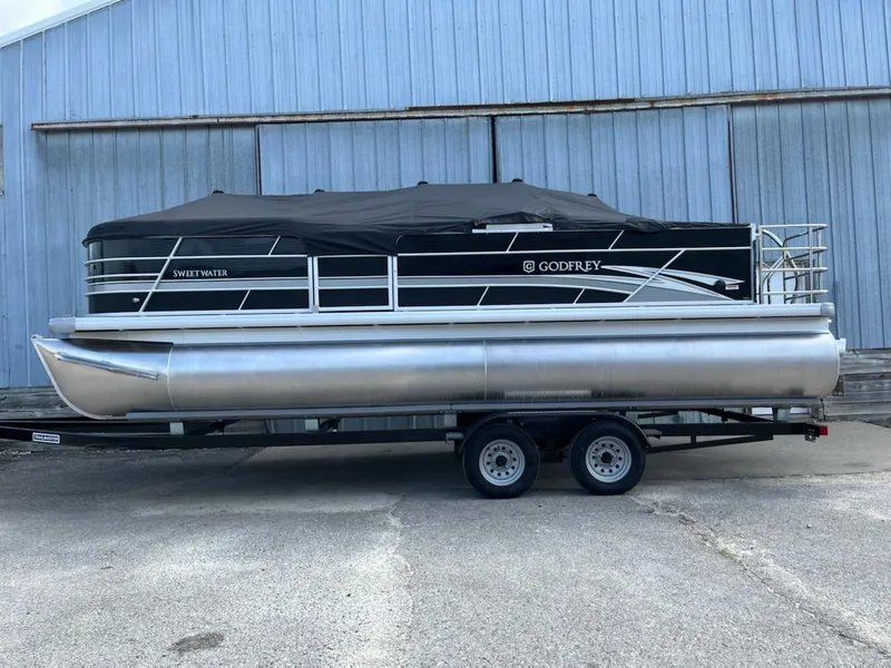 The Image of 2023 Sweetwater 2286SFL pontoon boat on a trailer, covered and parked. - 1