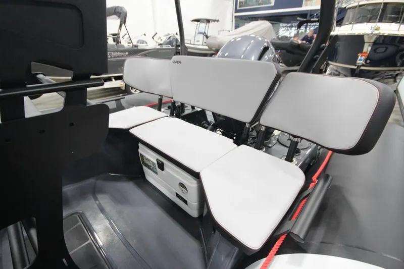 Slide: The Image of 2023 Zodiac Open 5.5 PVC boat with T-Top on trailer, parked outside a blue building. - 6