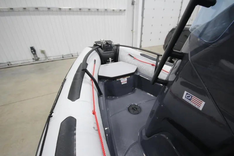 Slide: The Image of 2023 Zodiac Open 5.5 PVC boat interior with T-Top, featuring seating and red ropes. - 13