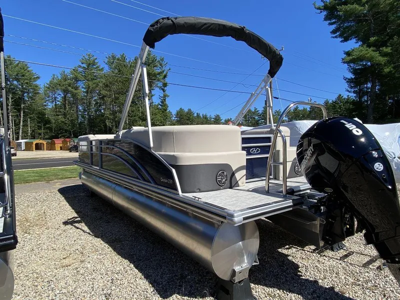 Slide: The Image of 2023 Harris Cruiser 250 CWDH pontoon boat on gravel lot, sunny day, trees in background. - 3