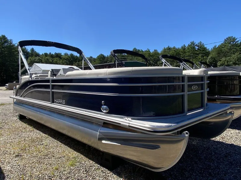Slide: The Image of 2023 Harris Cruiser 250 CWDH pontoon boat on gravel, surrounded by trees. - 5