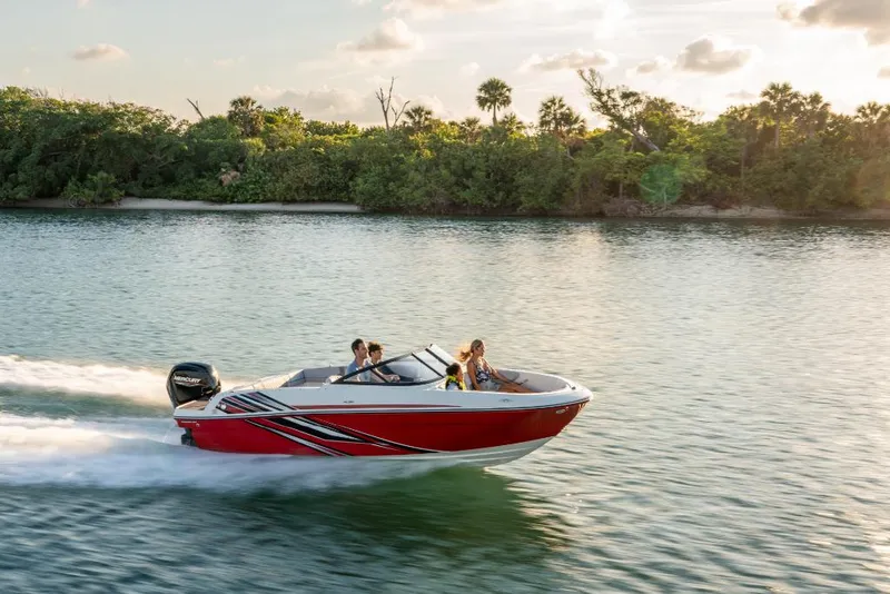 Slide: The Image of 2023 Bayliner M17 boat cruising on a serene lake with lush greenery in the background. - 17