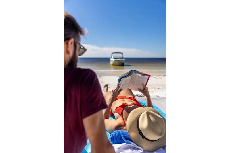 Slide: The Image of Couple relaxing on beach with 2023 Bayliner DX2000 boat in background. - 44
