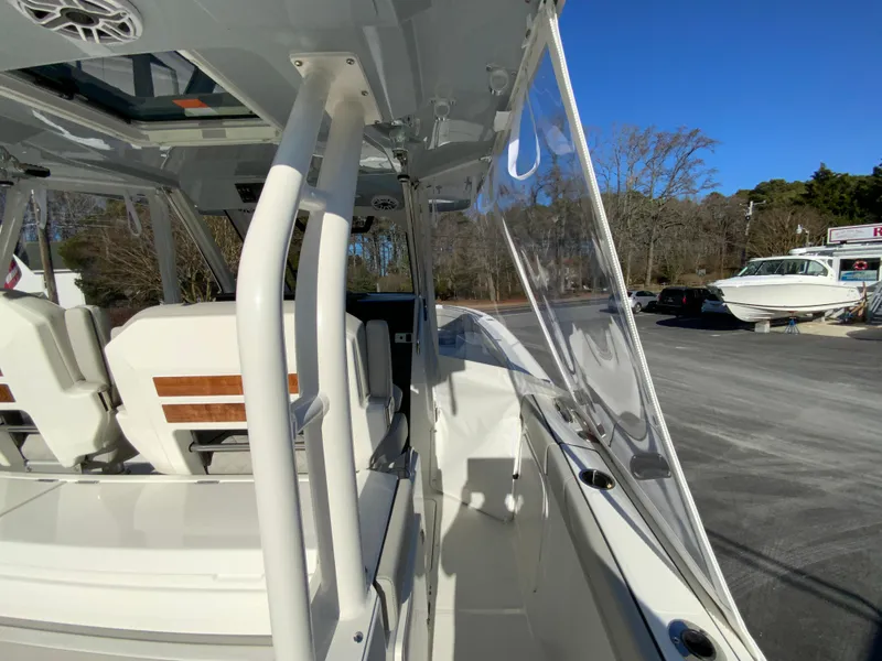 Slide: The Image of 2024 Pursuit S 328 Sport boat interior with white seating and clear side panels. - 21