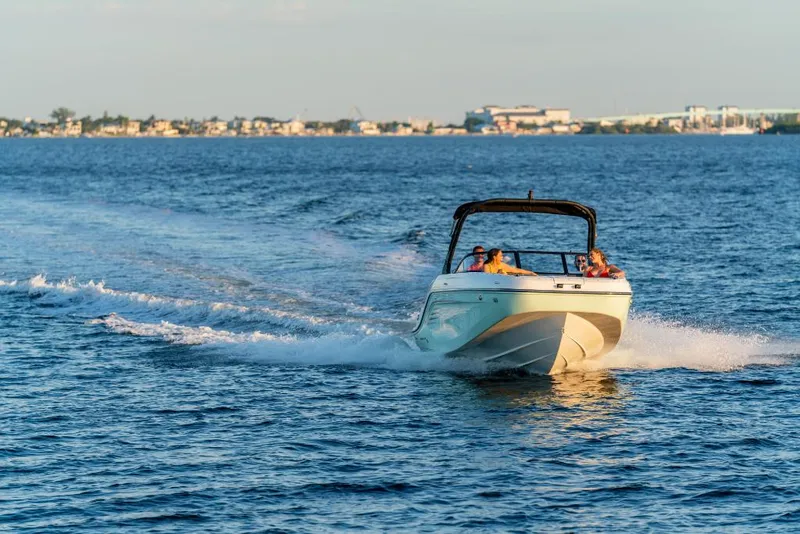 Slide: The Image of 2023 Bayliner DX2200 boat cruising on open water near the coastline. - 10