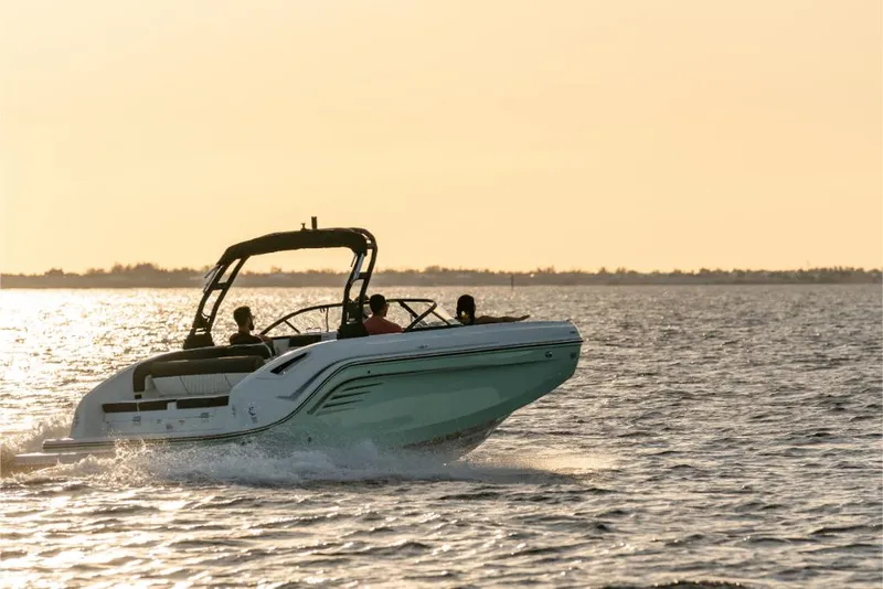 Slide: The Image of 2023 Bayliner DX2200 boat cruising on water at sunset. - 2