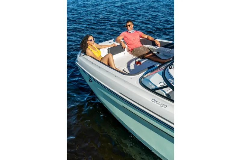 Slide: The Image of 2023 Bayliner DX2200 boat with two people relaxing on deck in open water. - 20