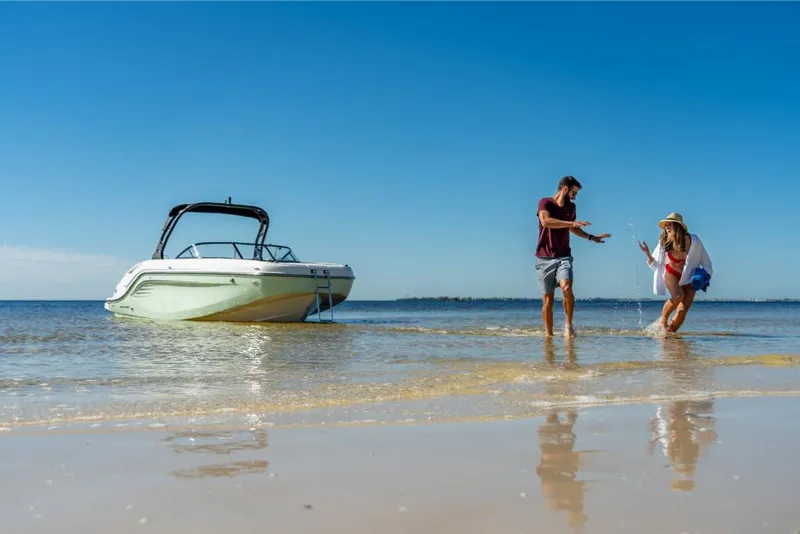 Slide: The Image of Couple enjoying beach near 2023 Bayliner DX2200 boat on a sunny day. - 25