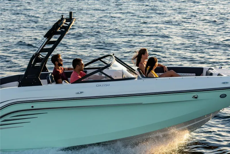 Slide: The Image of 2023 Bayliner DX2200 boat cruising with passengers on a sunny day. - 5