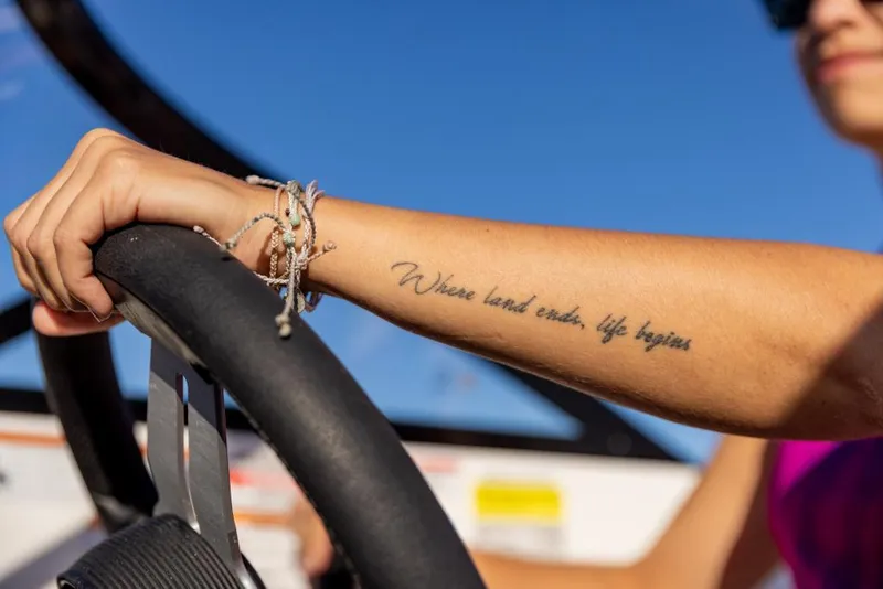 Slide: The Image of Person steering 2023 Bayliner DX2250 boat, tattoo reads Where land ends, life begins. - 45