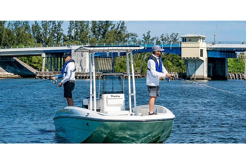 Slide: The Image of 2023 Bayliner T21 boat with two people fishing on a calm river near a bridge. - 6