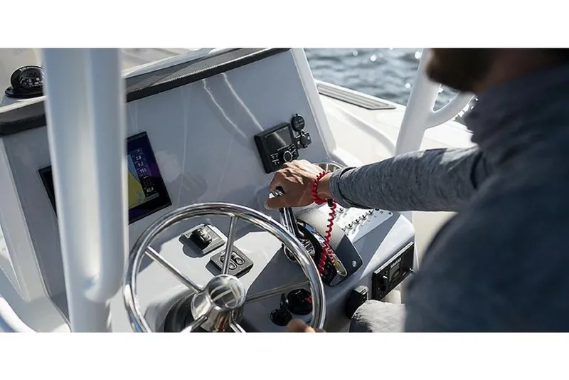 Slide: The Image of Person operating the helm of a 2023 Bayliner T24 CC boat. - 5
