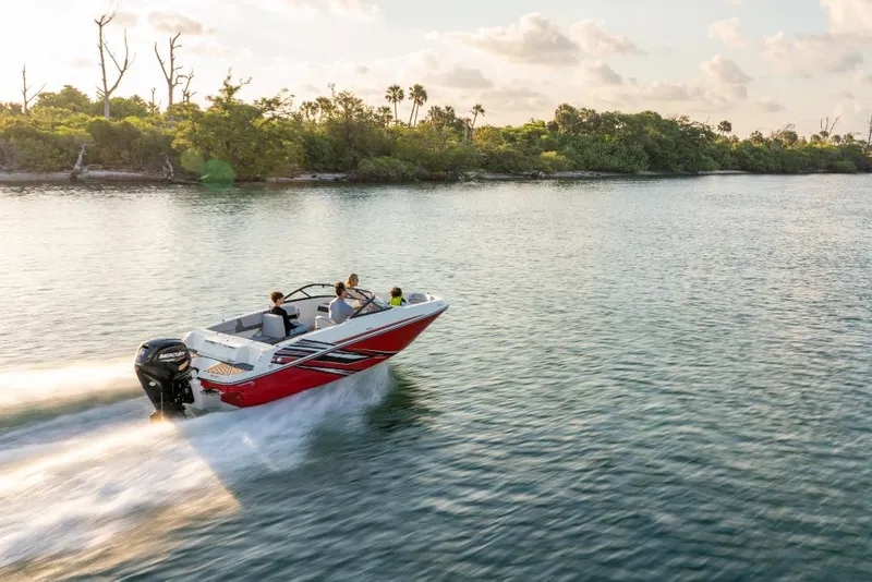 Slide: The Image of 2023 Bayliner VR4 Bowrider speeding on a serene lake with lush greenery. - 16