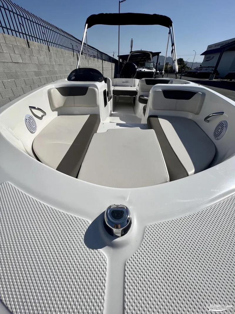 Slide: The Image of 2023 Bayliner E18 boat interior with seating and canopy, docked outdoors. - 3