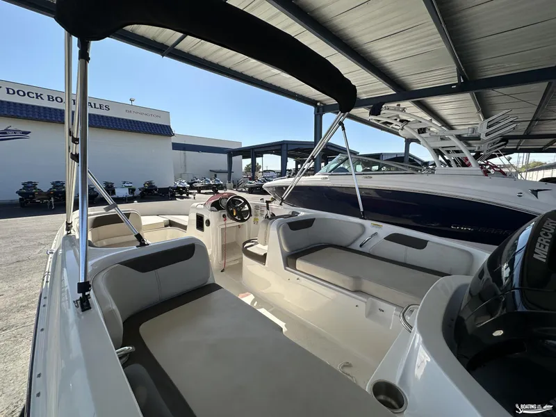 Slide: The Image of 2023 Bayliner E18 boat interior under a covered dock at a sales location. - 9