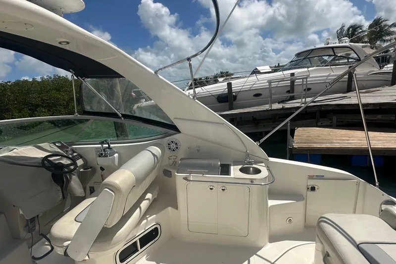 Slide: The Image of 2011 Sea Ray Sundancer 280 interior with helm, seating, and docked boats in background. - 36