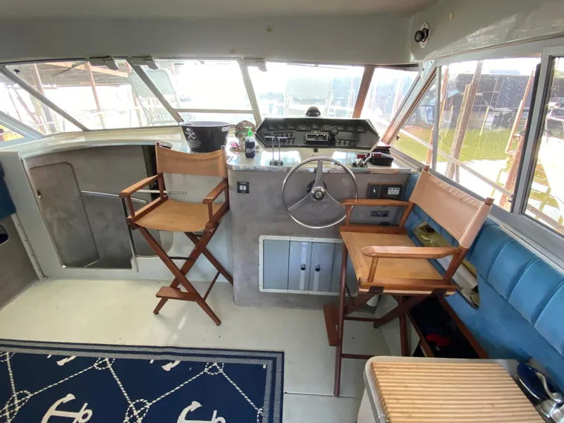Slide: The Image of 1984 Trojan 10 Meter Sedan boat interior with helm, wooden chairs, and nautical decor. - 22