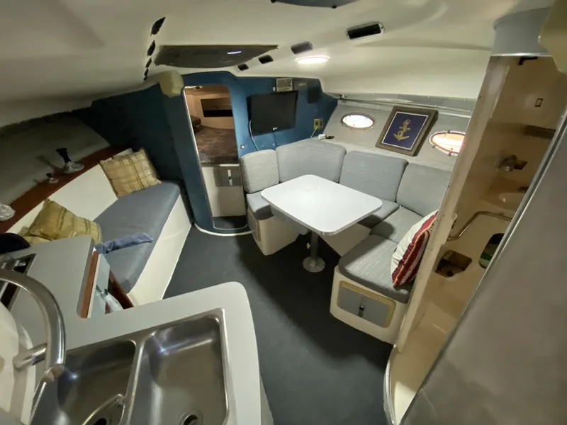 Slide: The Image of 1984 Trojan 10 Meter Sedan interior with seating area, table, and kitchenette. - 27