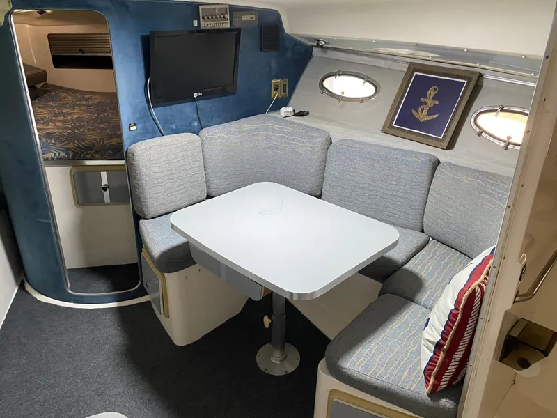 Slide: The Image of 1984 Trojan 10 Meter Sedan interior with dining area, TV, and porthole windows. - 28