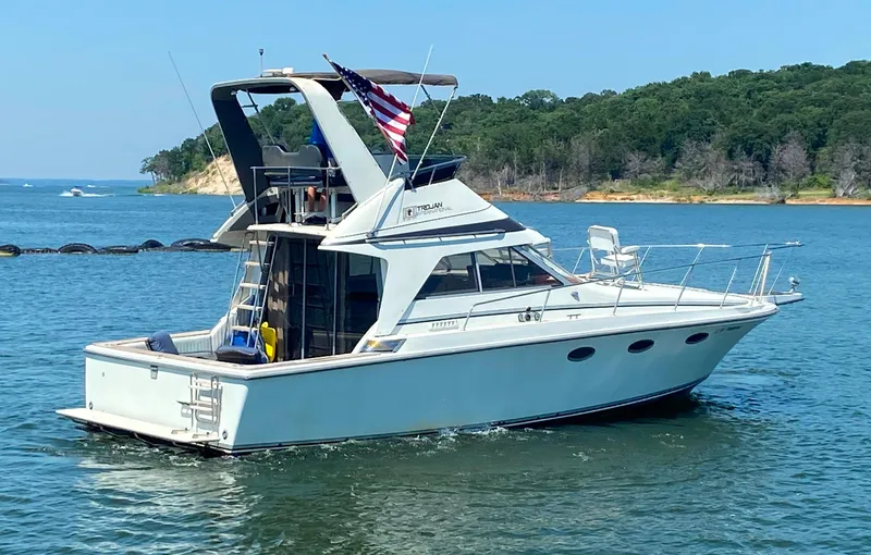 Slide: The Image of 1984 Trojan 10 Meter Sedan yacht cruising on a lake with forested shoreline. - 5