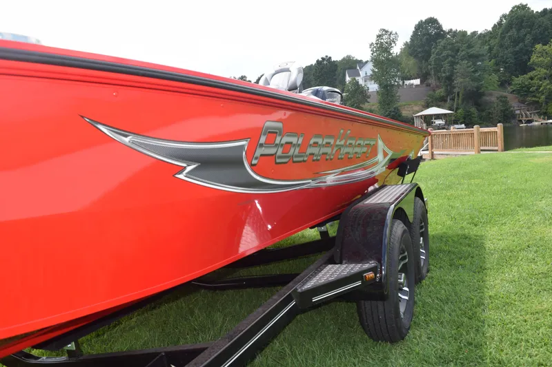 Slide: The Image of 2022 Polar Kraft Bass TX 195 Pro boat on trailer, red exterior, parked on grass. - 4