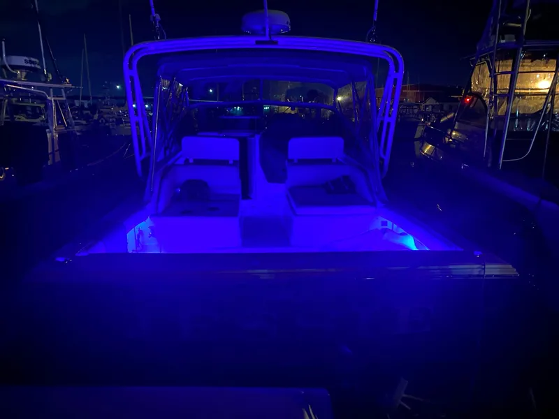 Slide: The Image of 1995 Blackfin 29-2 Combi boat illuminated with blue lights at night in a marina. - 8