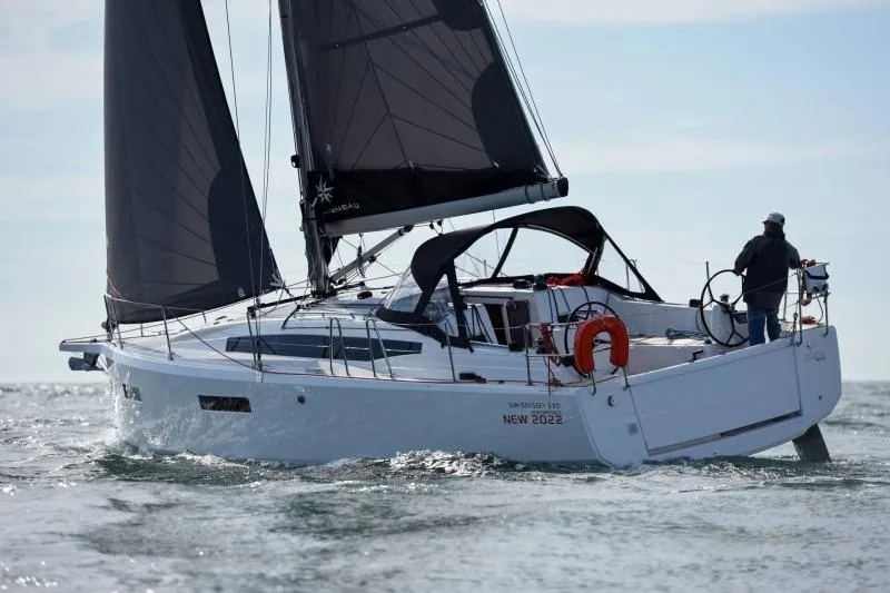 Slide: The Image of 2024 Jeanneau Sun Odyssey 380 sailing on open water, featuring sleek design and black sails. - 3