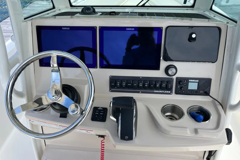 Slide: The Image of 2024 Boston Whaler 280 Dauntless helm with dual Simrad displays and stainless steel steering wheel. - 2