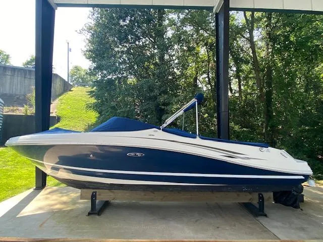 The Image of 2010 Sea Ray 230 Select boat with blue and white exterior, docked under a canopy. - 0