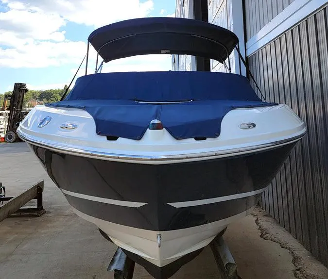 Slide: The Image of 2010 Sea Ray 230 Select boat with blue cover, docked near a building. - 1