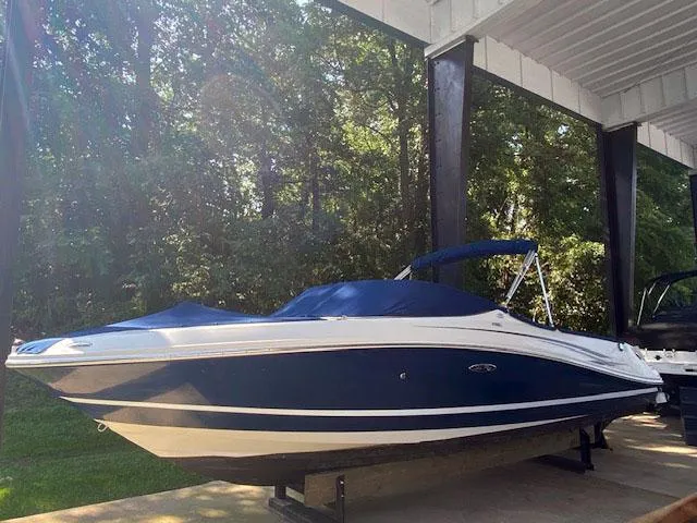 Slide: The Image of 2010 Sea Ray 230 Select boat with blue and white exterior, docked under a canopy. - 2